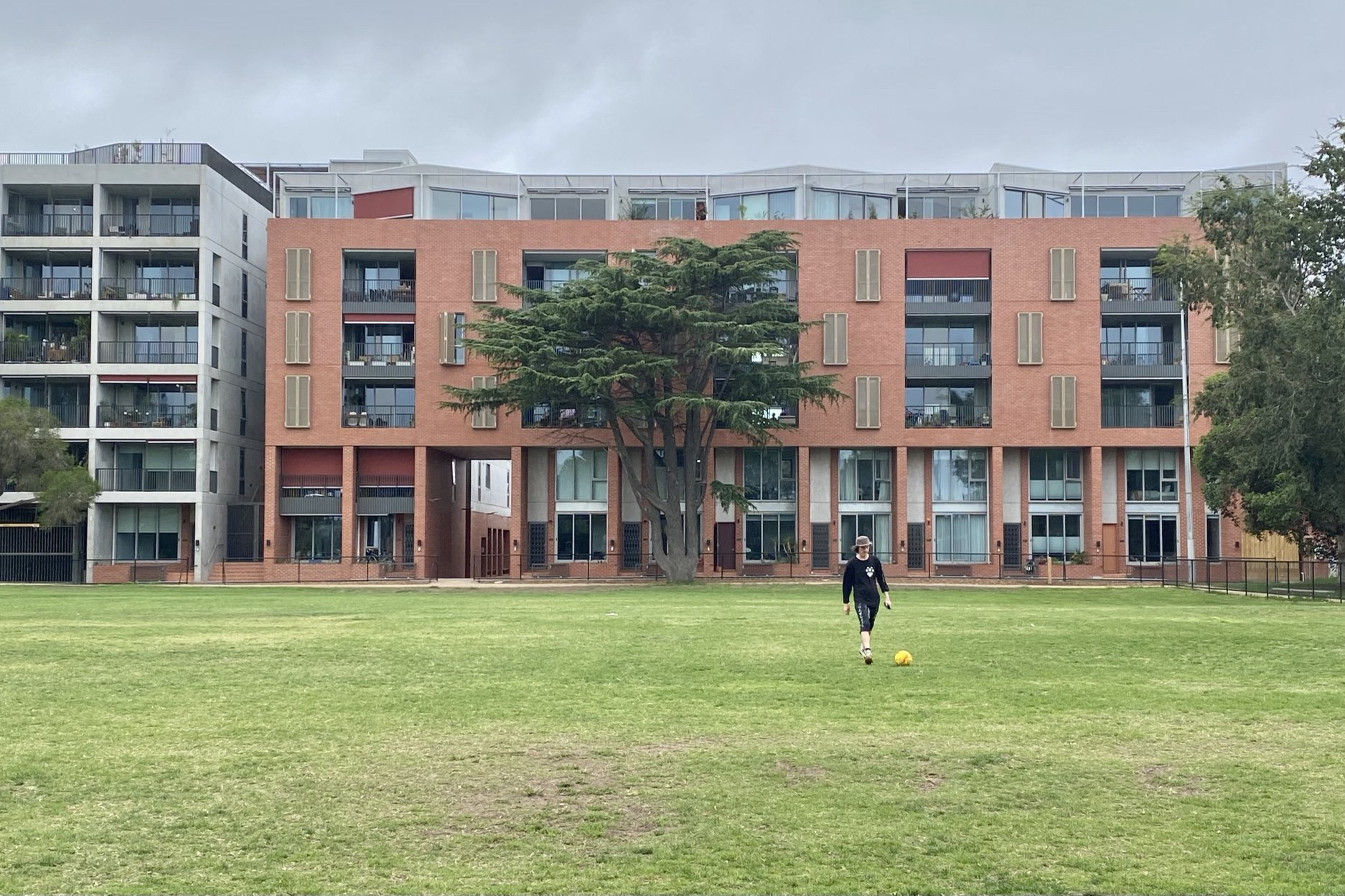 2 short apartment buildings side-by-side in front of a large grassy park.