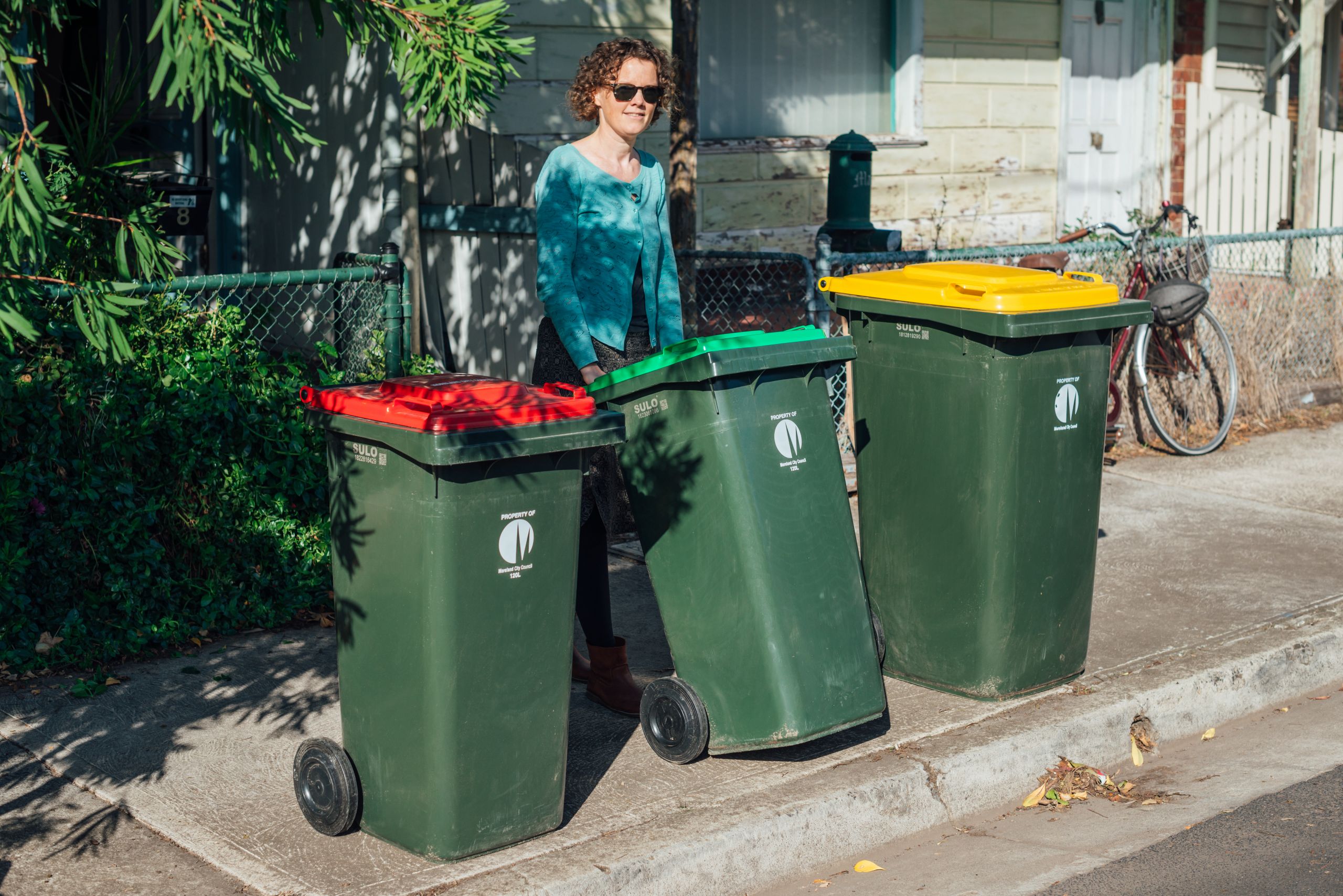 Woman putting green bin at kerbside