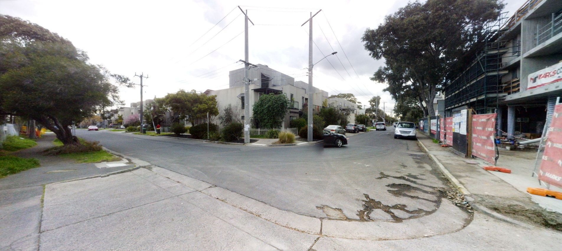 Before: A view from the curve of Stuart Street before the upgrades. the bitumen is cracked and there is a construction site to the right.